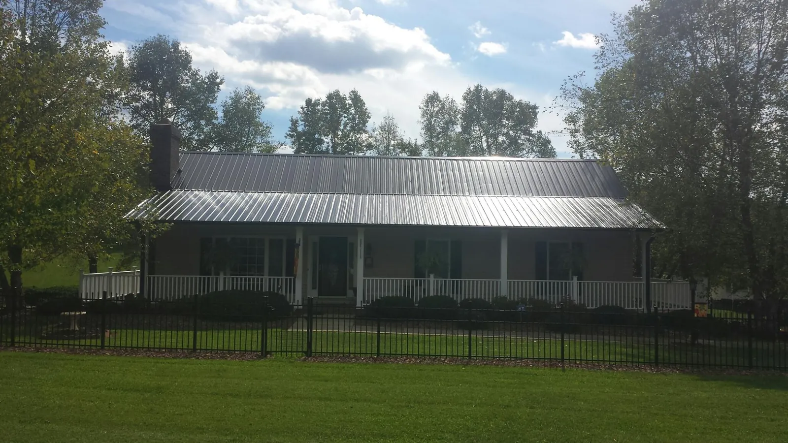 Gray metal roof on a brick ranch with a full width front porch — Gutter Guard Installation work by our crew in Denton